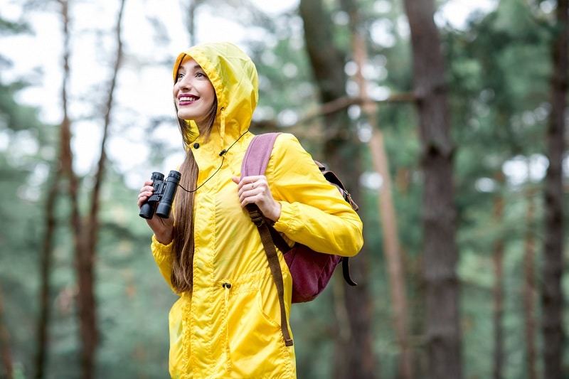 Girl standing in rain with roof prism binoculars